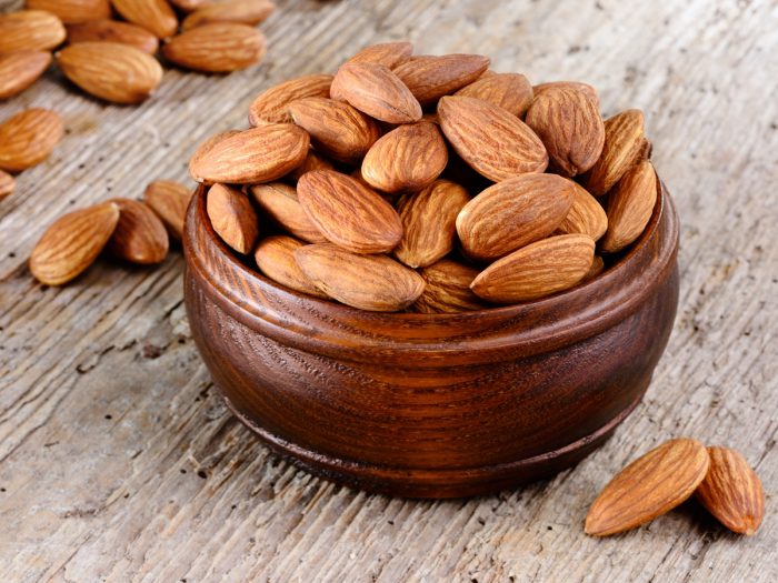 A bowl of almonds placed on a wooden table