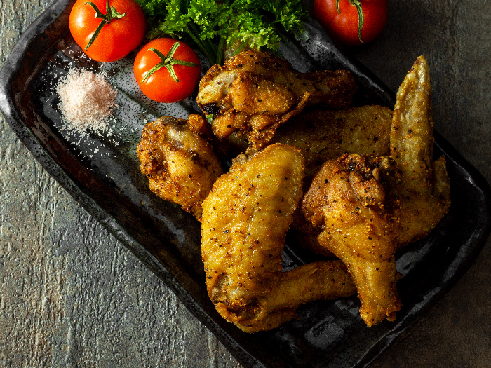 Fried chicken wings served with tomato and fine Himalayan salt garnish with parsley